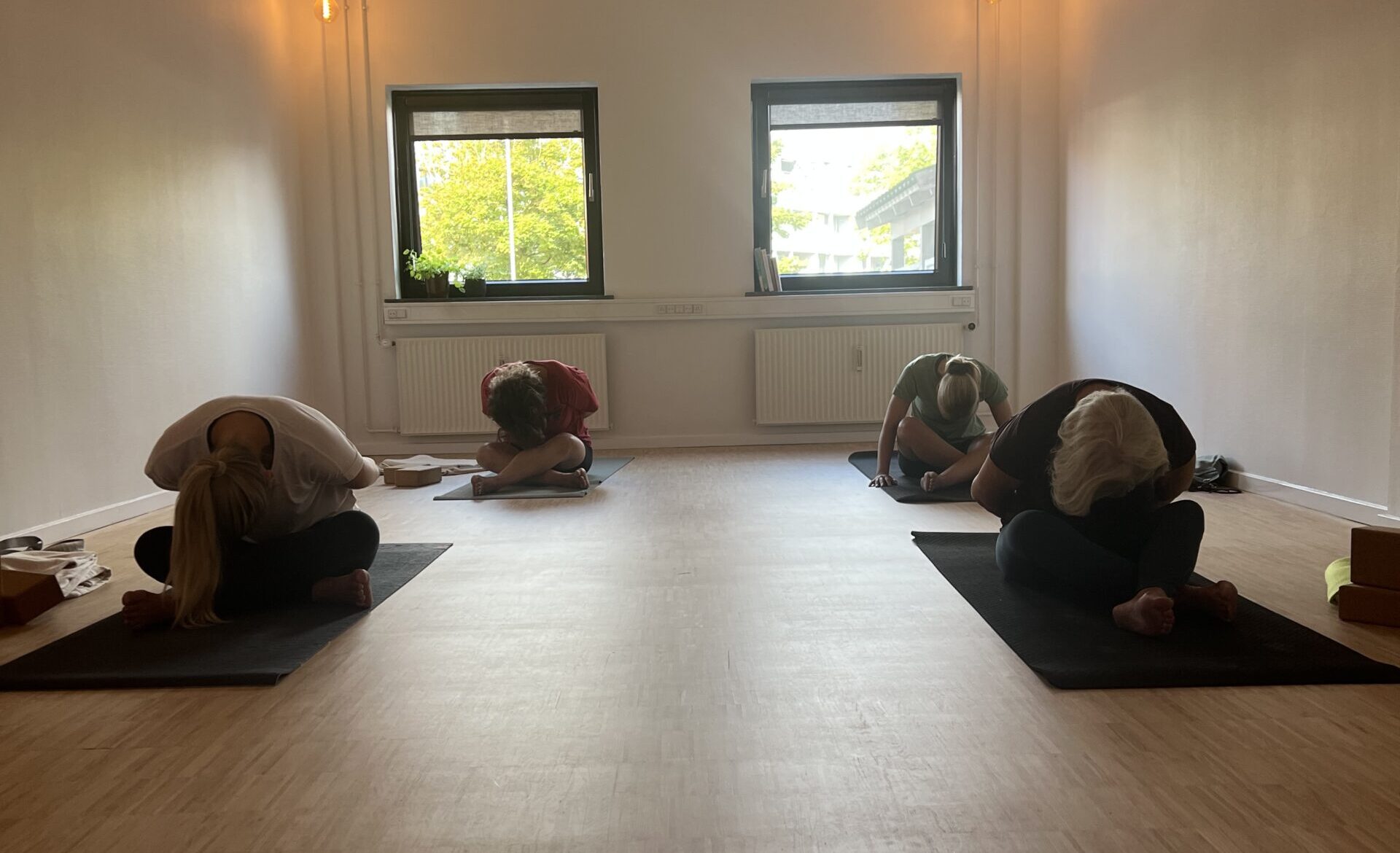 Yoga, yin yoga, yinpower® i esbjerg midtby. til alle aldre og niveauer. hjælper på hovedpine, artrose, får ro på nervesystemet og giver plads til at være dig. holistisk bevægelses studie miintaka. på billedet ser du 4 kvinder, der laver yoga, i stillingen kram barnet. et roligt øjeblik i studiet under en time.