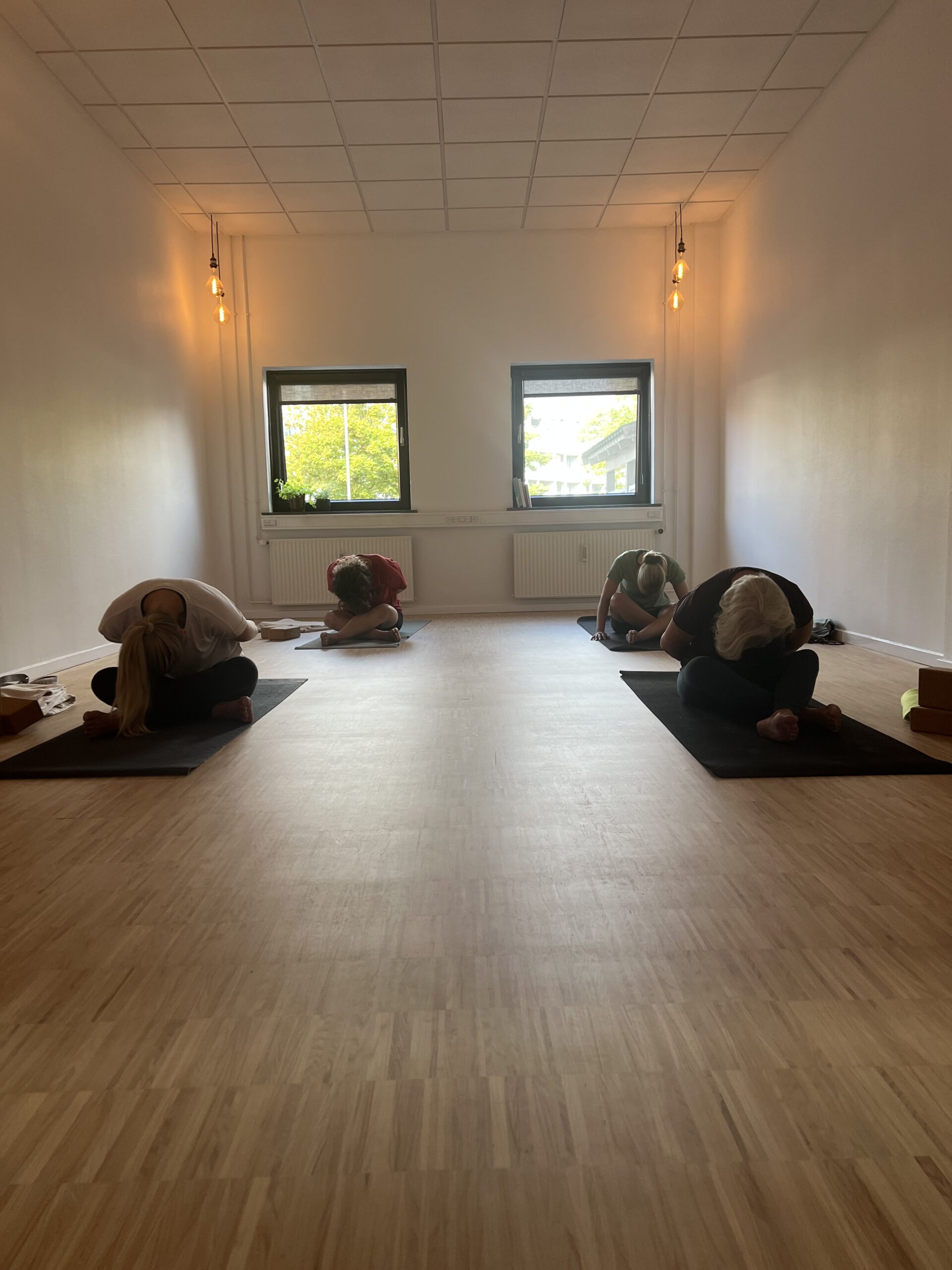 Yoga, yin yoga, yinpower® i esbjerg midtby. til alle aldre og niveauer. hjælper på hovedpine, artrose, får ro på nervesystemet og giver plads til at være dig. holistisk bevægelses studie miintaka. på billedet ser du 4 kvinder, der laver yoga, i stillingen kram barnet. et roligt øjeblik i studiet under en time.